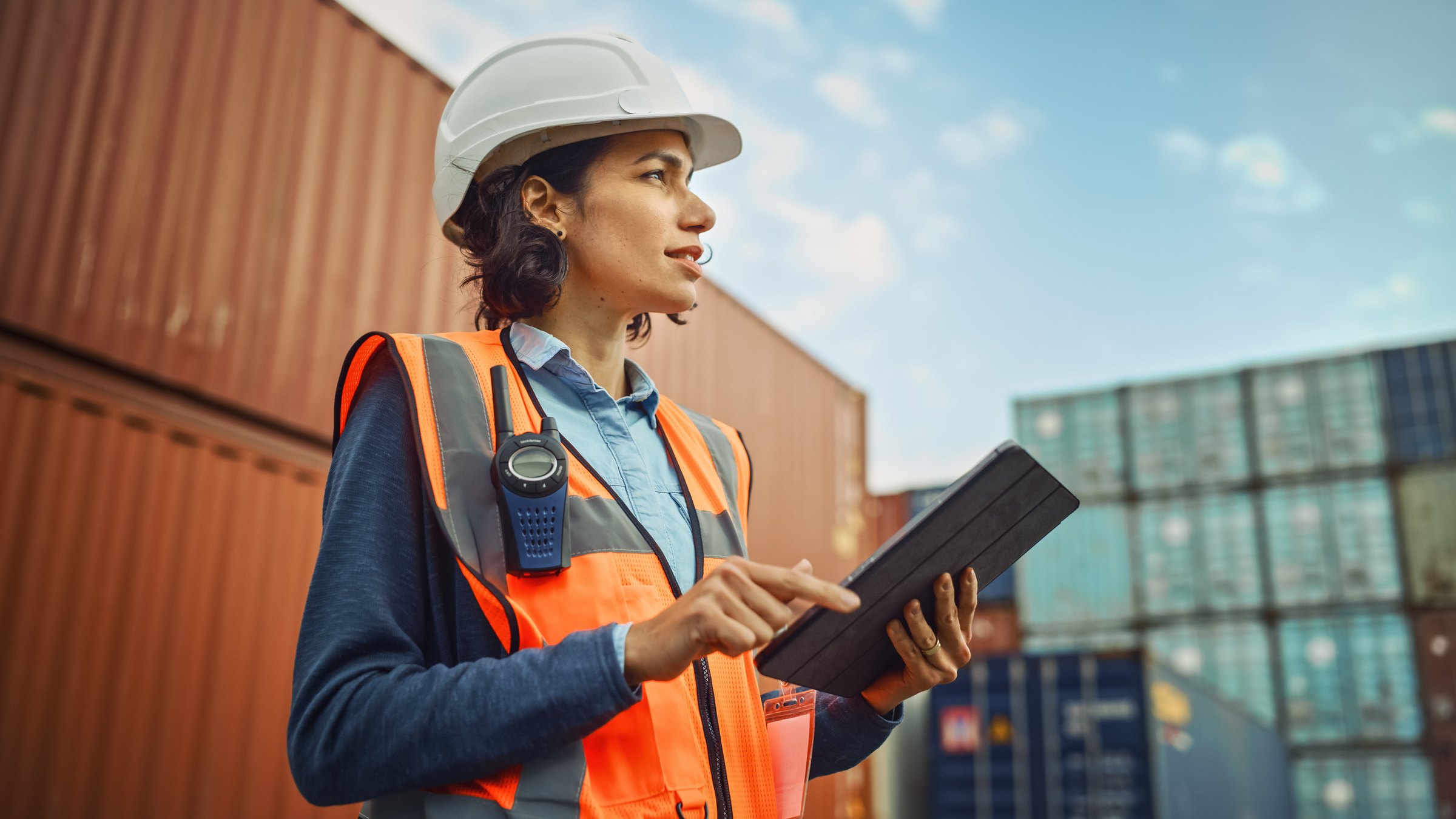 A safety supervisor reviewing a tablet at a container terminal